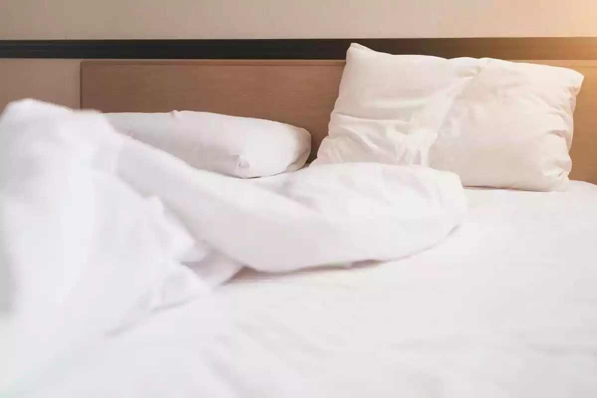 Foto de una cama con sábanas blancas
